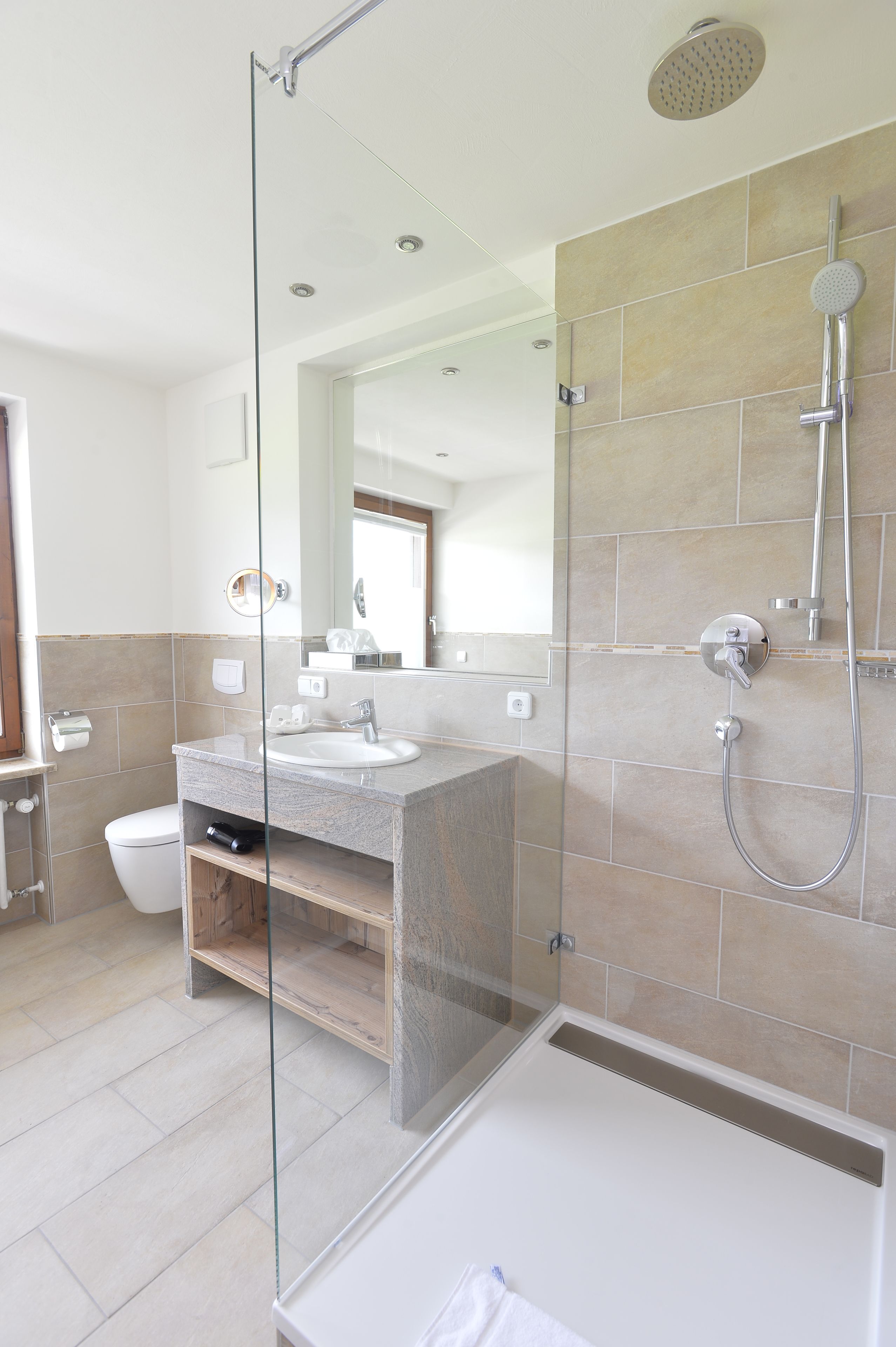 Ein modernes Badezimmer mit Duschkabine aus Glas, einem Waschbecken und einer Toilette.