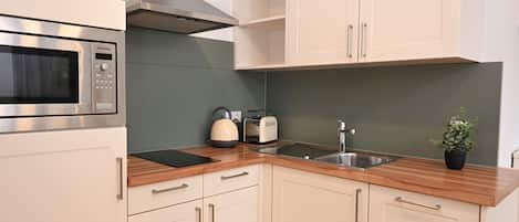 A modern kitchen with white cabinets, a stainless steel microwave, a toaster, and a sink.