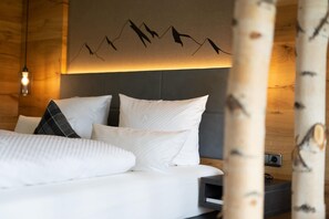 A bed with white bedding and a headboard against a wooden wall. - Alpenhof Oberstdorf Hotel & Spa, BW Signature Collection (Oberstdorf)