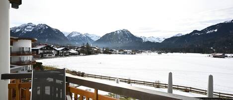 A balcony with a view of a snow-covered lake and mountains.