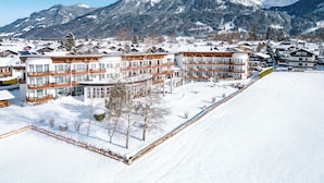 A snow-covered mountain resort with multi-story buildings, including a hotel with balconies and a ski slope. - Alpenhof Oberstdorf Hotel & Spa, BW Signature Collection (Oberstdorf)