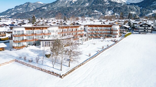 A snow-covered mountain resort with multi-story buildings, including a hotel with balconies and a ski slope. - Alpenhof Oberstdorf Hotel & Spa, BW Signature Collection (Oberstdorf)