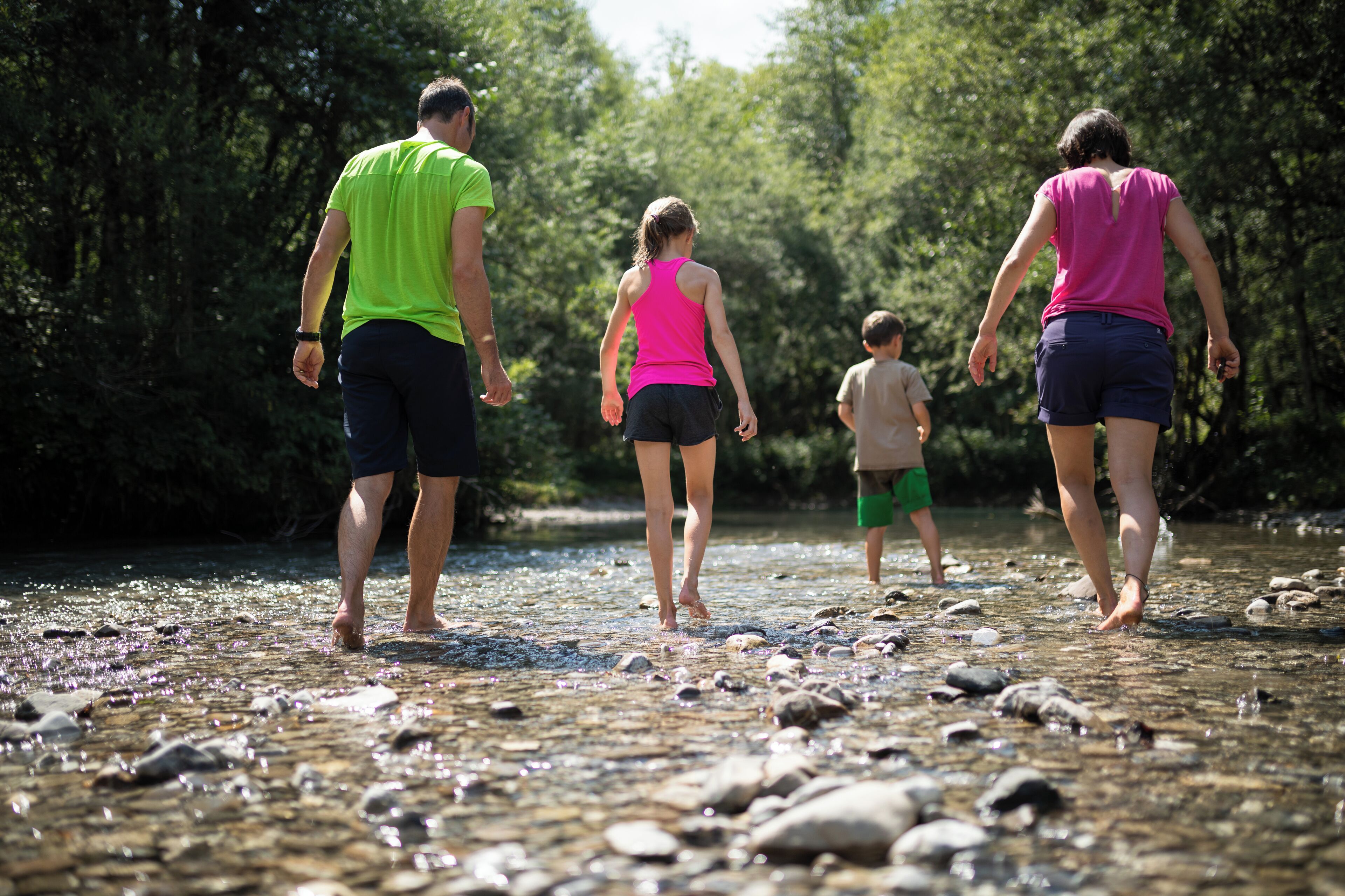 A group of people walking along a rocky riverbank.