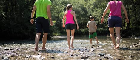 A group of people walking along a rocky riverbank.