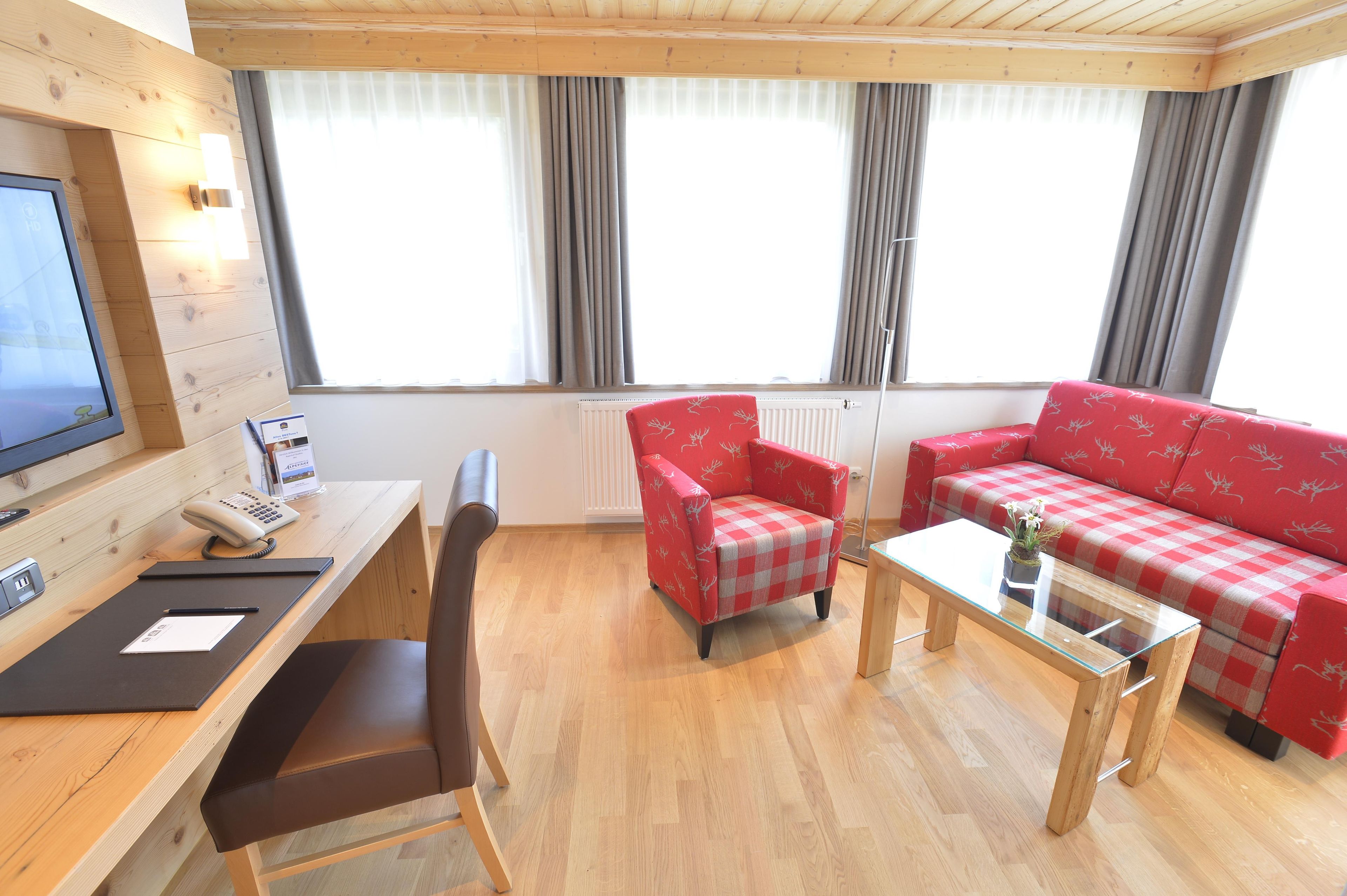 Una habitación amoblada con escritorio, silla, sofá y una mesa de centro de vidrio.