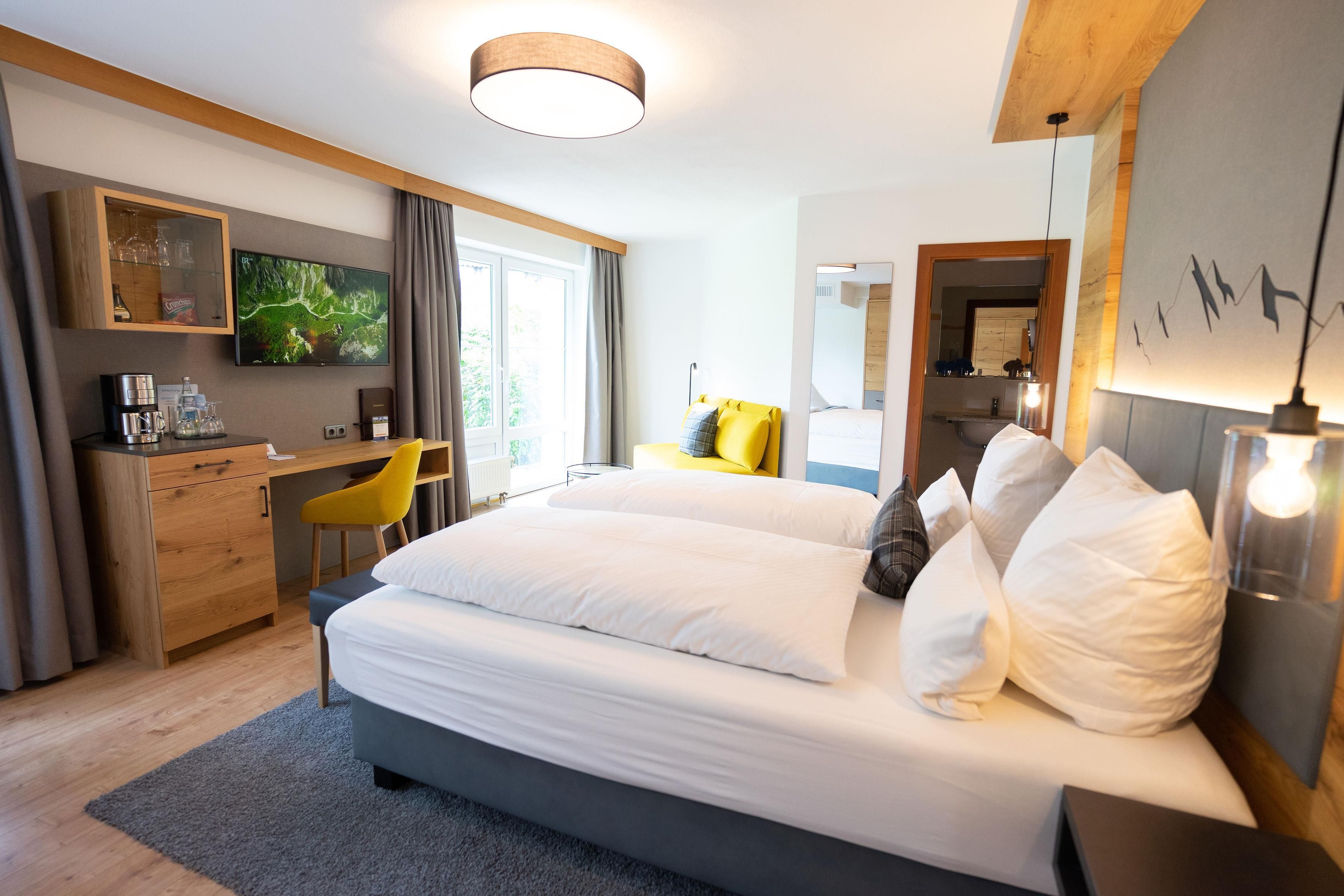 Una habitación de hotel moderna con una cama grande, un escritorio, una silla y un televisor.