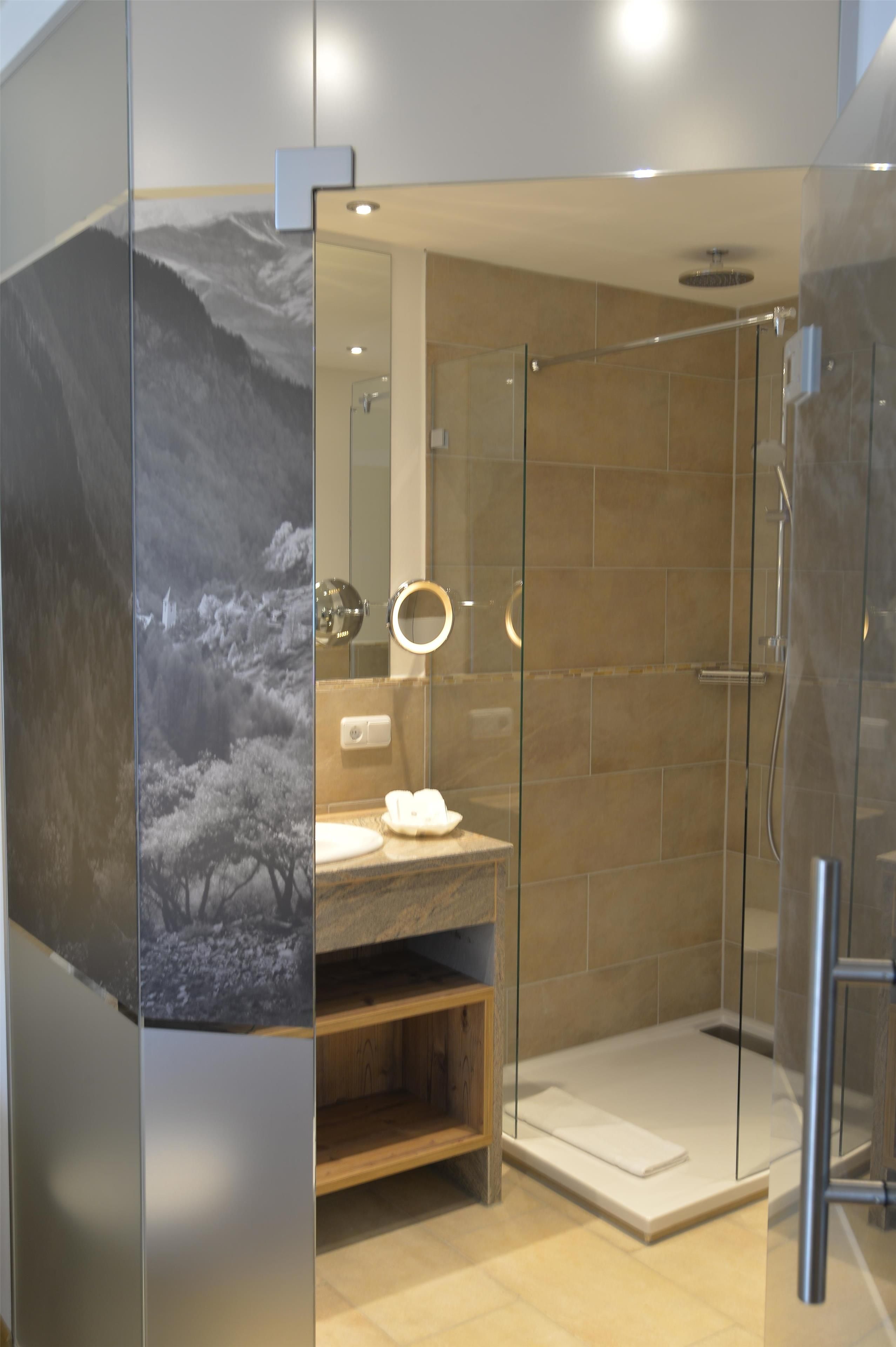Ein modernes Badezimmer mit Duschkabine aus Glas, Waschtisch mit Spiegel und Wand-WC.