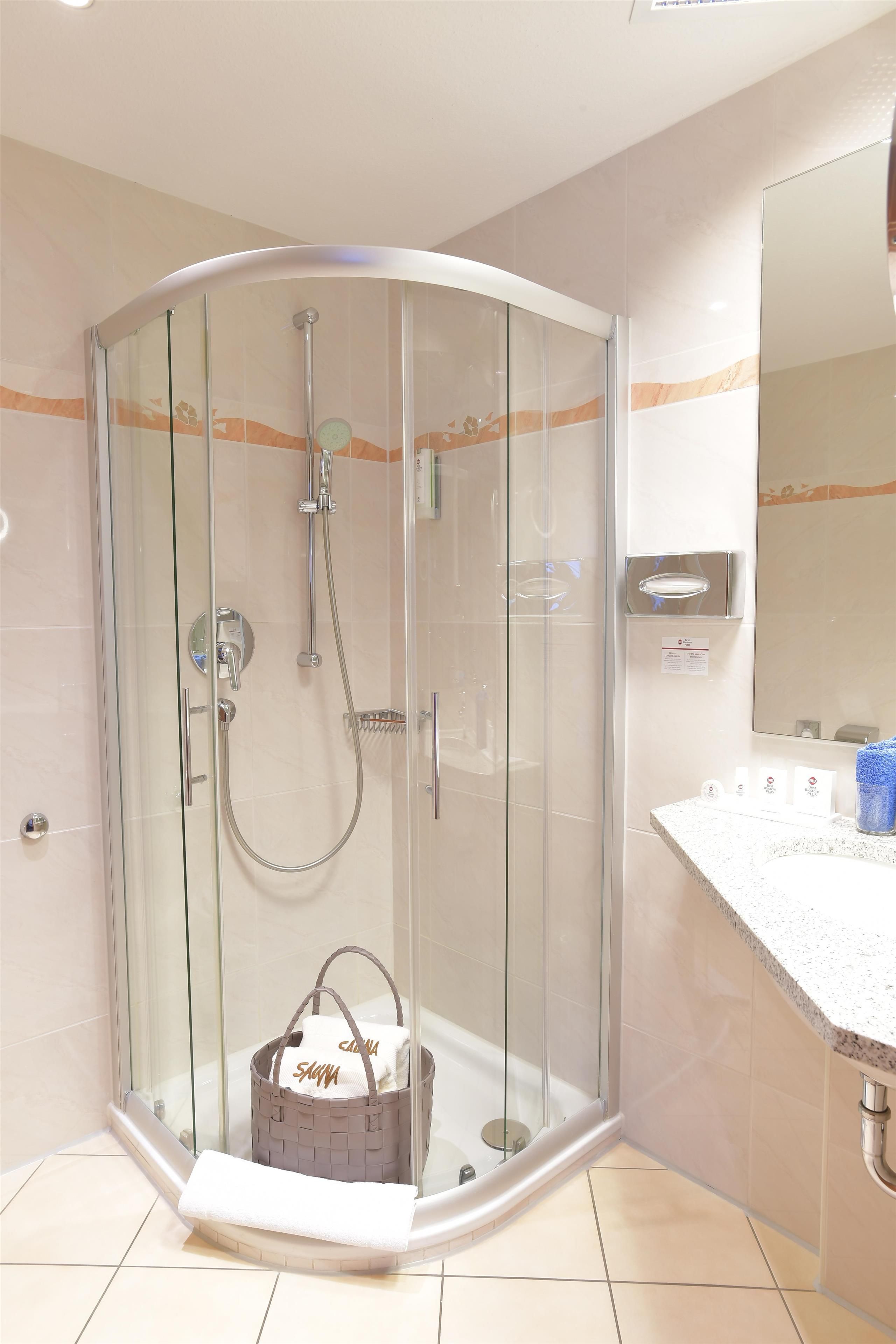 Un baño moderno con ducha envuelta en vidrio, tocador con espejo y perchero.