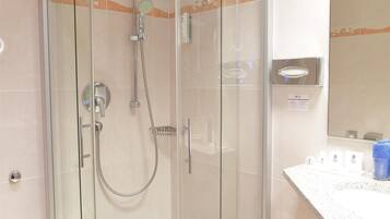 Un baño moderno con ducha envuelta en vidrio, tocador con espejo y perchero.