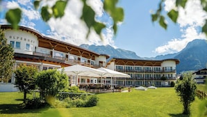 A hotel with multiple balconies, outdoor seating, and a mountainous backdrop. - Alpenhof Oberstdorf Hotel & Spa, BW Signature Collection (Oberstdorf)