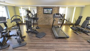 A gym with treadmills, elliptical machines, and a television screen on the wall. - Alpenhof Oberstdorf Hotel & Spa, BW Signature Collection (Oberstdorf)