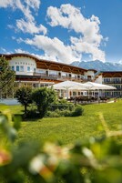 Un hotel con varios balcones, mobiliario exterior y vistas a las montañas.