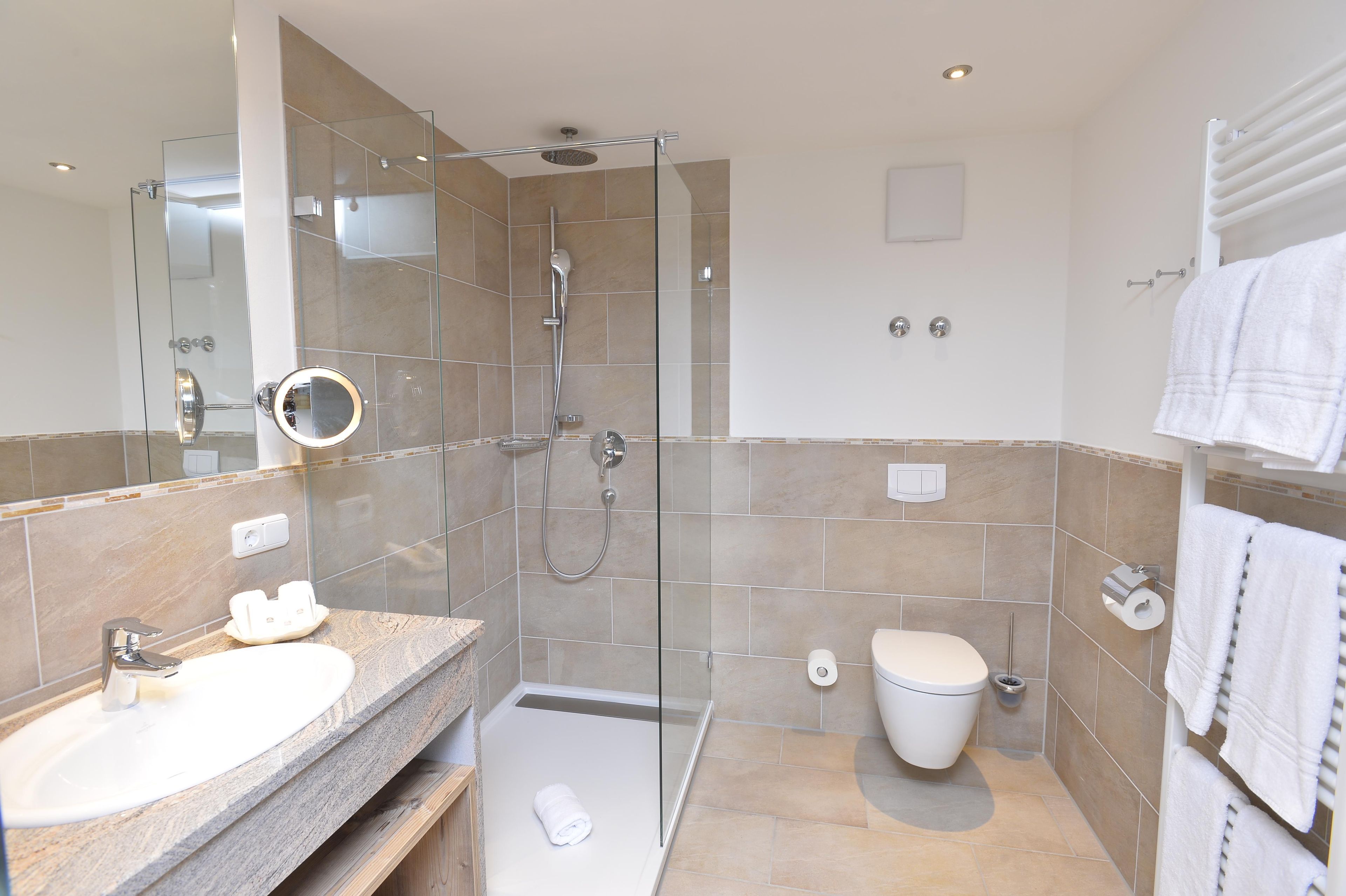Une salle de bain moderne avec une douche à parois de verre, un lavabo avec un miroir, des toilettes et un porte-serviettes.