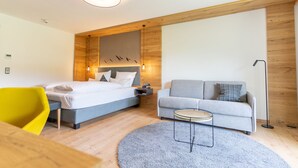 A modern hotel room with a bed, a sofa, a small table, and a chair. - Alpenhof Oberstdorf Hotel & Spa, BW Signature Collection (Oberstdorf)