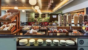 A buffet area with various food options and a seating area with tables and chairs. - Novotel Wellington (Wellington)