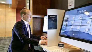 A man using a Mac desktop computer in a hotel setting.