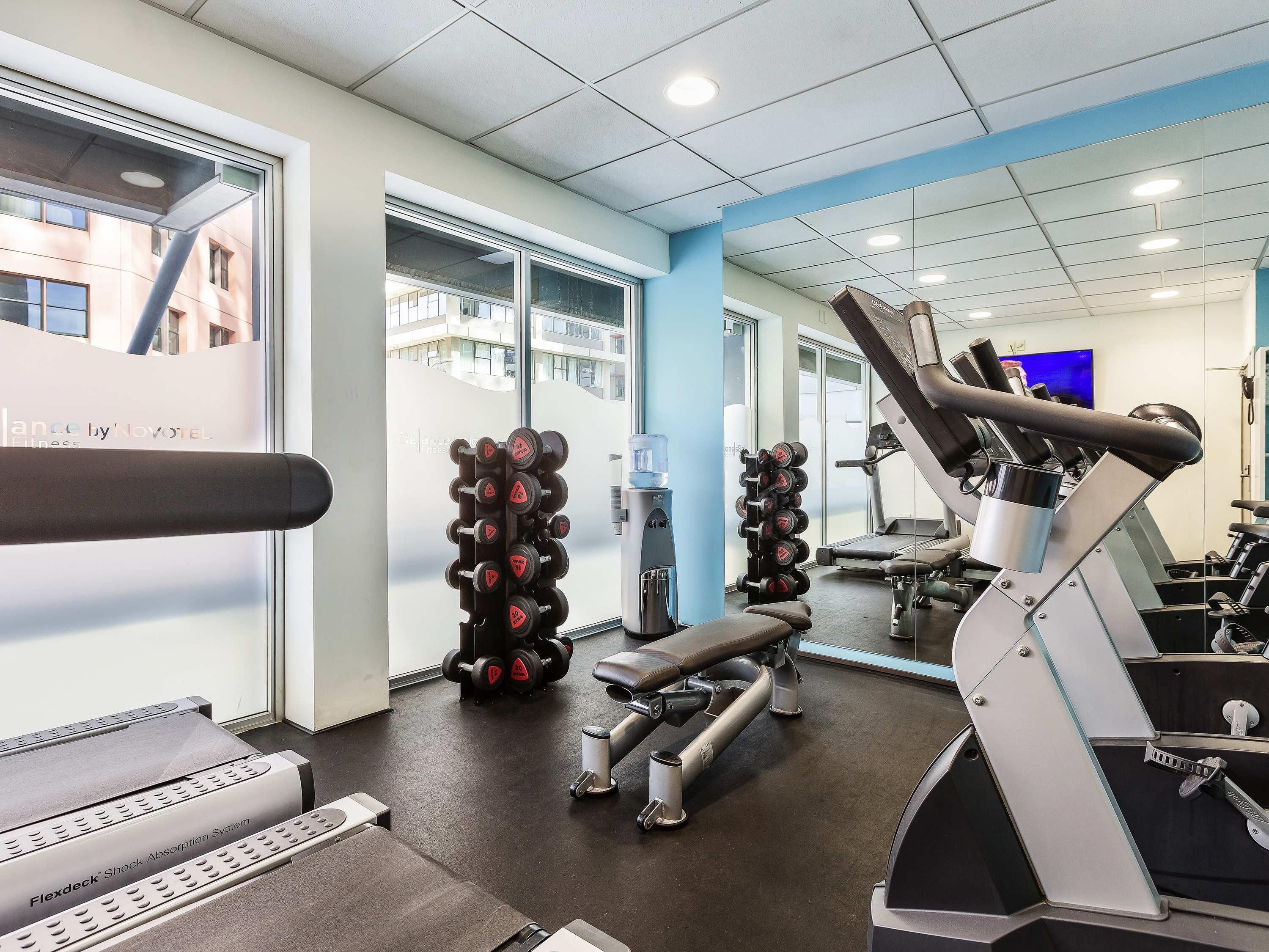 A modern gym with cardio equipment, weight racks, and a water dispenser.