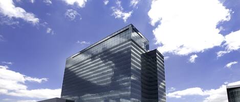 A modern glass building with a flat roof, surrounded by trees and a clear sky.