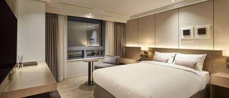 A modern hotel room with a large bed, a desk, and a window with curtains.