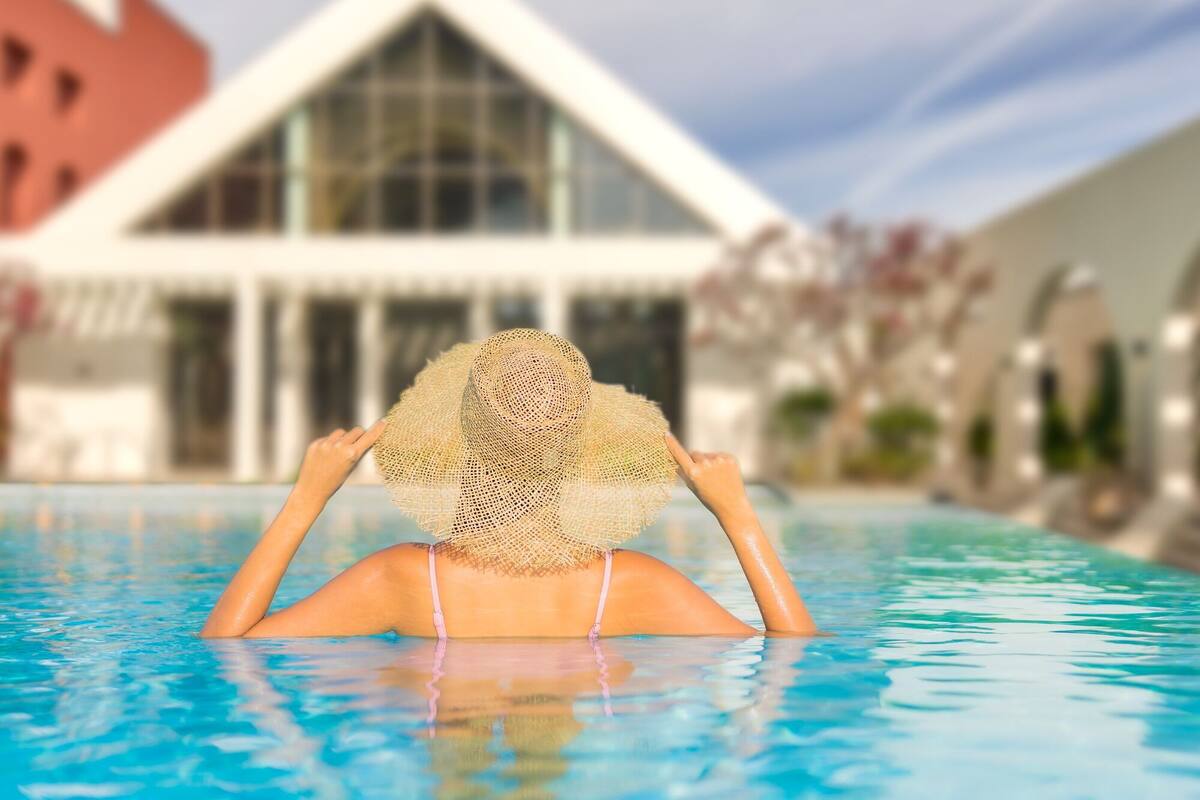 A person in a swimming pool with a house in the background.