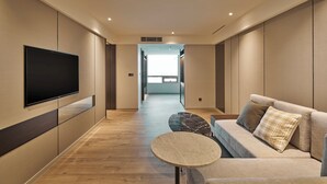 Una sala de estar moderna con un sofá, una pequeña mesa redonda y un televisor de pantalla plana montado en la pared.