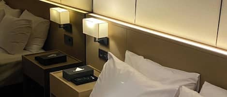 Una habitación de hotel con una cama bien hecha, una mesita de noche con lámpara y un panel de control en la pared.