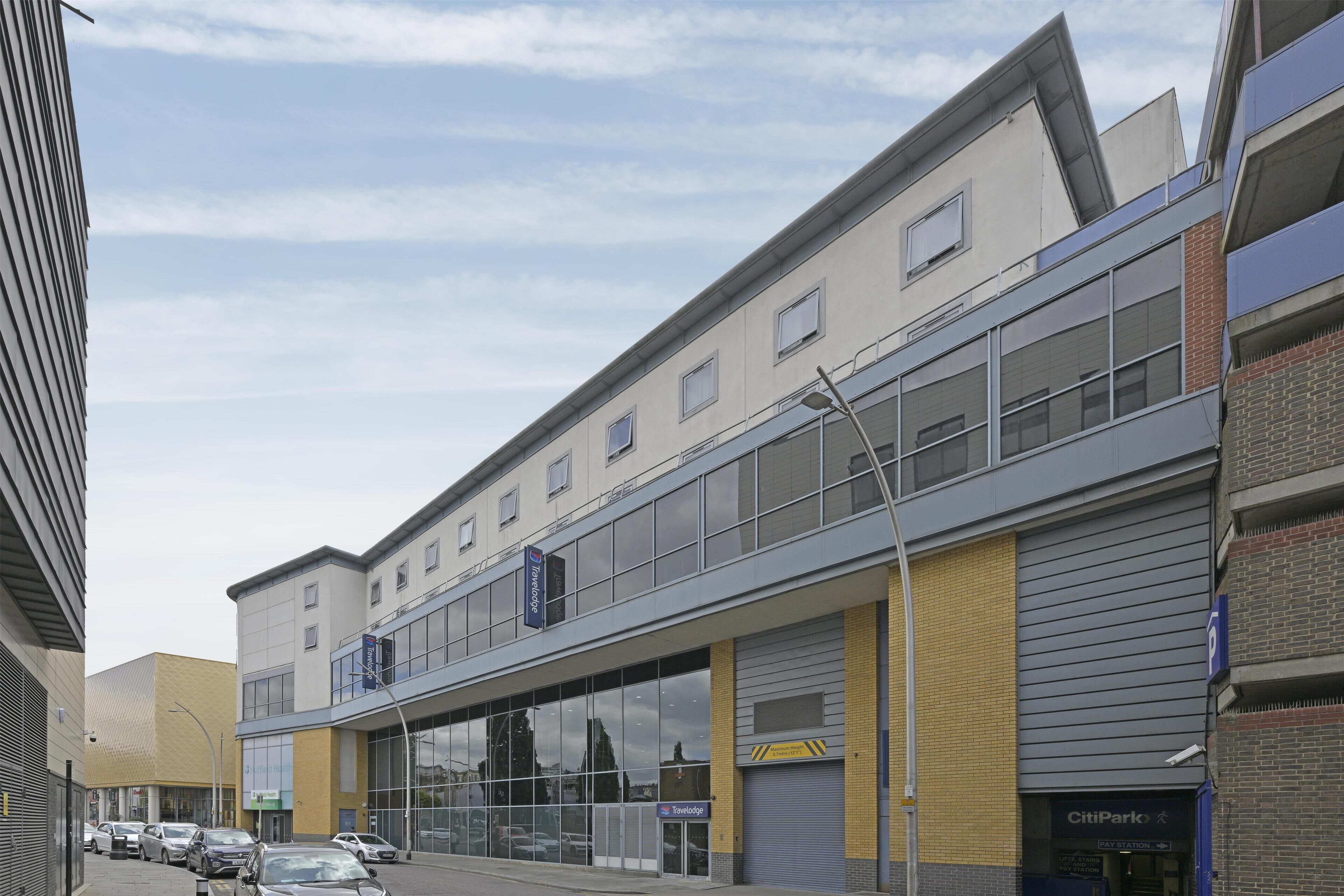 A multi-story building with large windows, a covered entrance, and a parking sign.