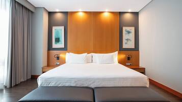 Een moderne hotelkamer met een groot bed, twee nachtkastjes en een houten hoofdeinde.