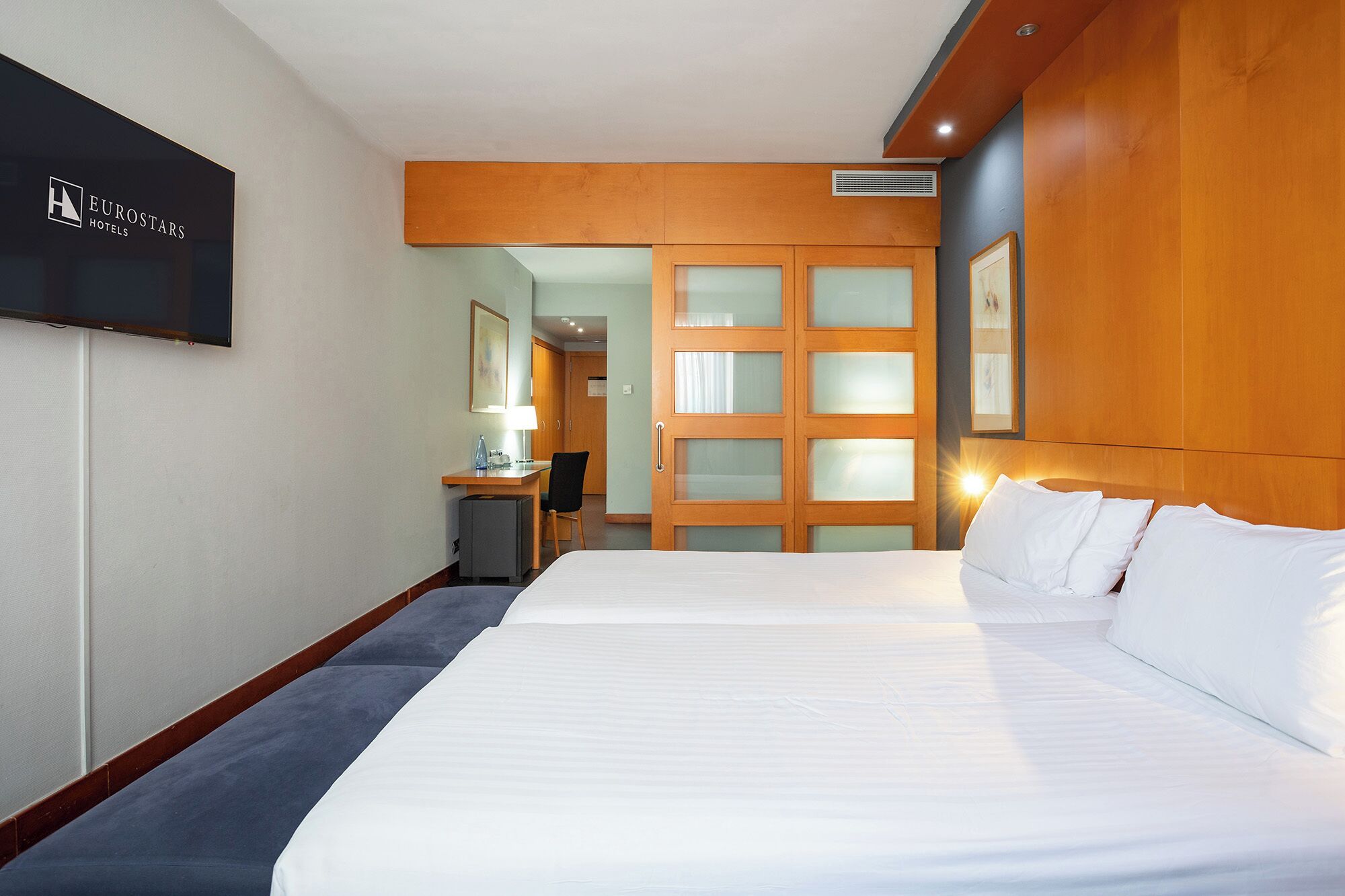 Une chambre d’hôtel avec un grand lit, un bureau, une chaise et un téléviseur.