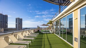 A rooftop terrace with sun loungers, a small table, and potted plants. - Eurostars Atlantida (Santa Cruz de Tenerife)
