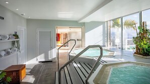 A modern indoor pool area with clear glass walls, a view of the ocean, and a shower area with towels and plants. - Eurostars Atlantida (Santa Cruz de Tenerife)