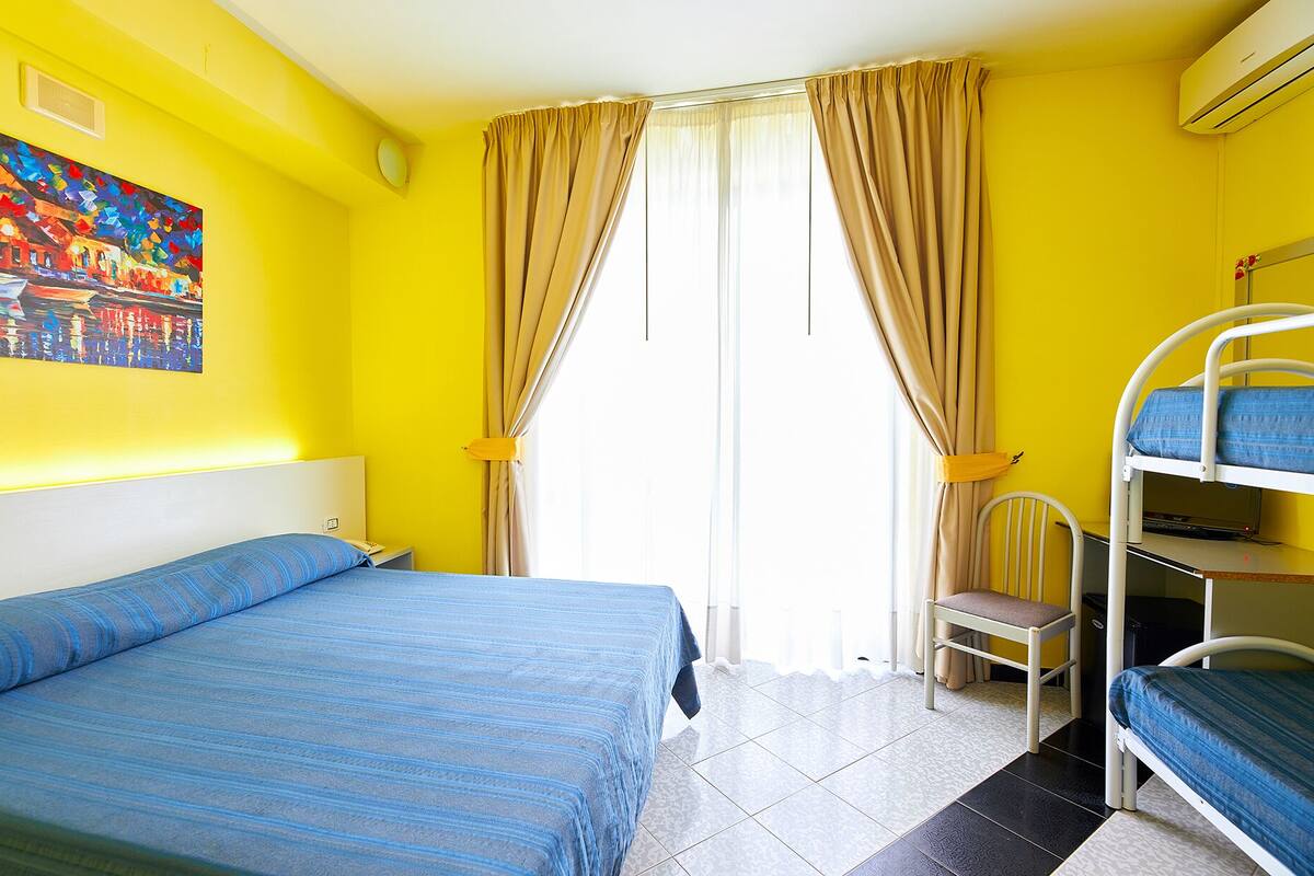 A room with a bed, a bunk bed, a chair, and a painting on the wall.