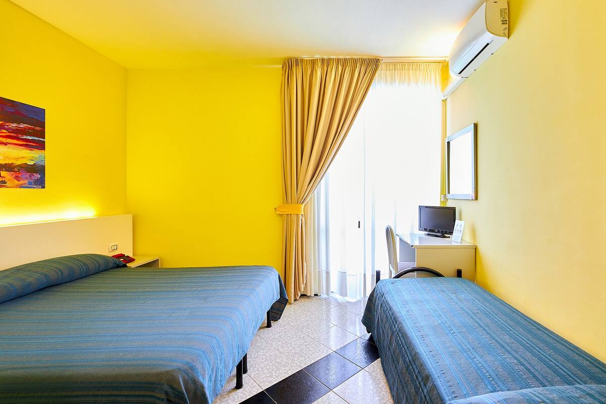 A hotel room with two beds, a TV, and a painting on the wall.
