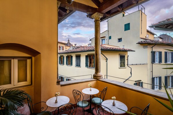 Enjoy the classic European views from this charming balcony with a wrought iron railing, small table, and two chairs.