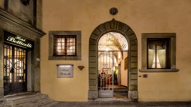 Exterior del Hotel Botticelli, con una entrada arqueada, un cartel y una ventana con cortinas.
