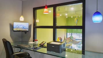 A modern office space with a glass desk, a computer monitor, a printer, and a chair.