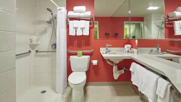 Un baño con inodoro blanco, ducha, lavabo y espejo.