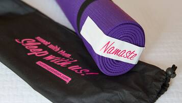 Una colchoneta morada enrollada con la etiqueta "Namaste" y una colchoneta negra con texto rosa.