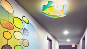 Un pasillo con una decoración circular y colorida en la pared y una alfombra estampada.