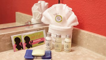 Un meuble-lavabo de salle de bain avec une serviette blanche, une trousse de produits pour le nettoyage du visage et un emballage de démaquillant avec l'inscription « Enlevez tout ! ».