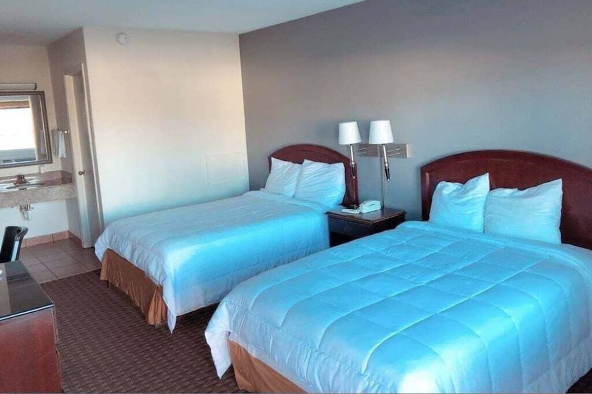 Habitación de hotel con dos camas, un escritorio y una ventana.