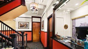 A hotel lobby with a staircase, a reception desk, and a cityscape view. - Mithila San Francisco, SureStay Collection by Best Western (San Francisco)