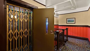 A hotel entrance with a decorative metal gate, a framed picture on the wall, and a patterned carpet. - Mithila San Francisco, SureStay Collection by Best Western (San Francisco)