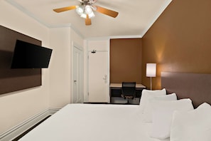 A hotel room with a large bed, a desk, a chair, a television, and a ceiling fan. - Mithila San Francisco, SureStay Collection by Best Western (San Francisco)