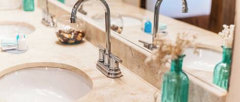 A bathroom with three sinks, each with a modern faucet, and a large mirror above the sinks.