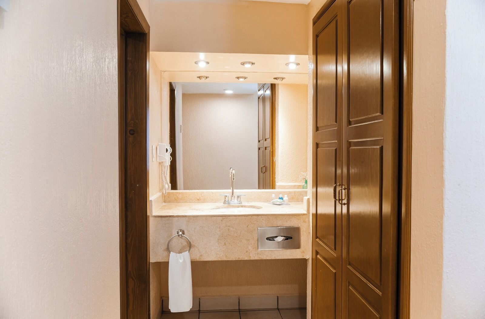 Un baño con lavamanos, espejo y puerta de madera.