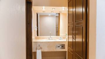 Un baño con lavamanos, espejo y puerta de madera.