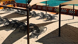 Un café frente a la playa con terraza y sombrillas, con vistas al mar.