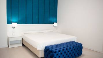 A bedroom with a bed, bedside tables, and a blue upholstered bench.