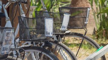 Una bicicleta con un cartel que dice 'Bike 4' sujeto a su estructura, estacionada cerca de una valla metálica.